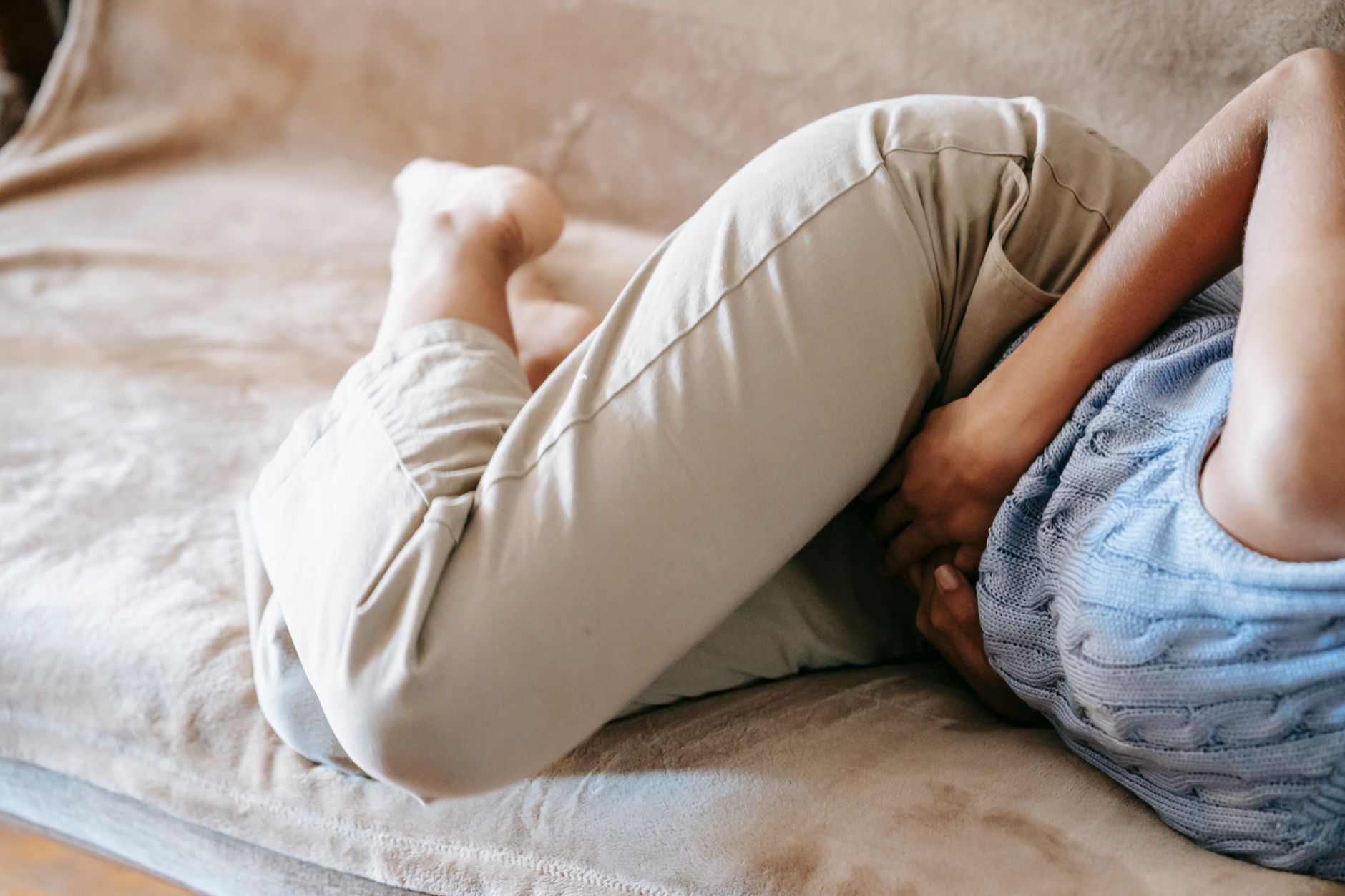 月経のつらさで体調がすぐれず、ソファで体を丸めて休む女性