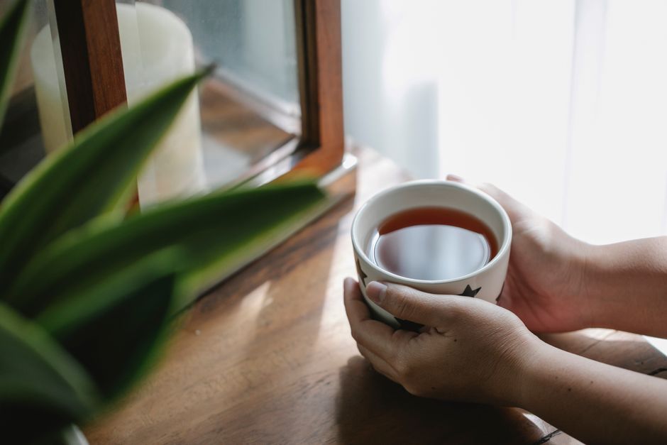 窓辺で温かいお茶を両手で包む、就寝前のリラックスした様子