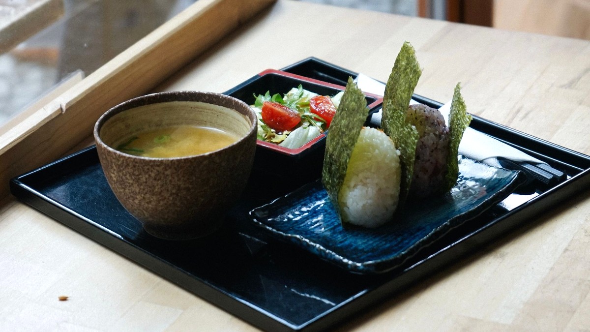 明るい木のテーブルに置かれた、湯気の立つ汁物の椀と和食の膳