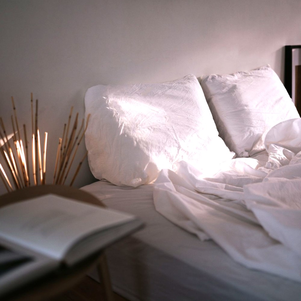 朝の光が差し込む寝室の白い寝具。長引く痛みが睡眠や日常生活を損なうことを表す静かな室内