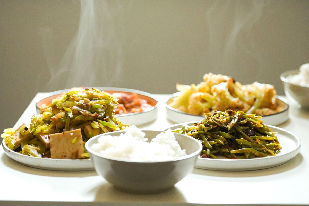 明るい食卓のトレイに並んだ、ごはんと野菜・豆腐の小皿がいくつも置かれた家庭の食事