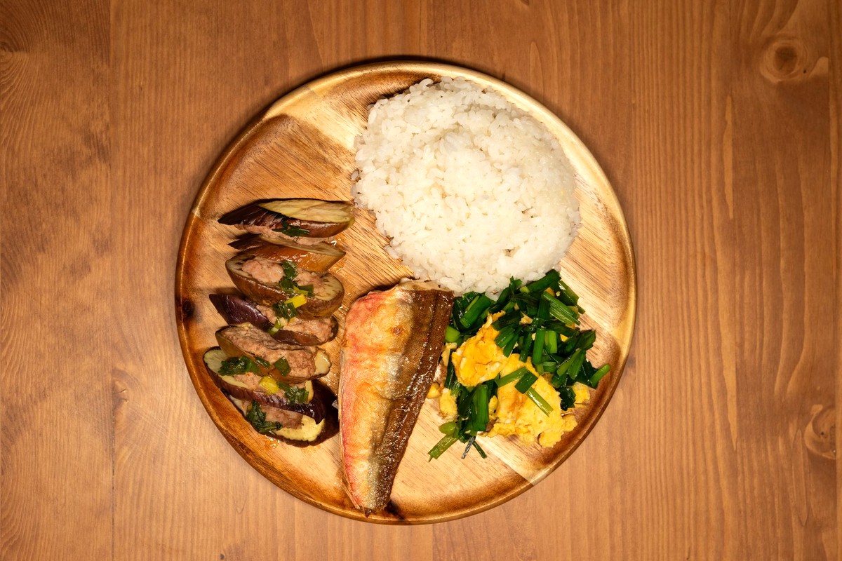 木の丸皿に盛られた、ごはん・焼き魚・青菜のおひたしなどの普段どおりの和食