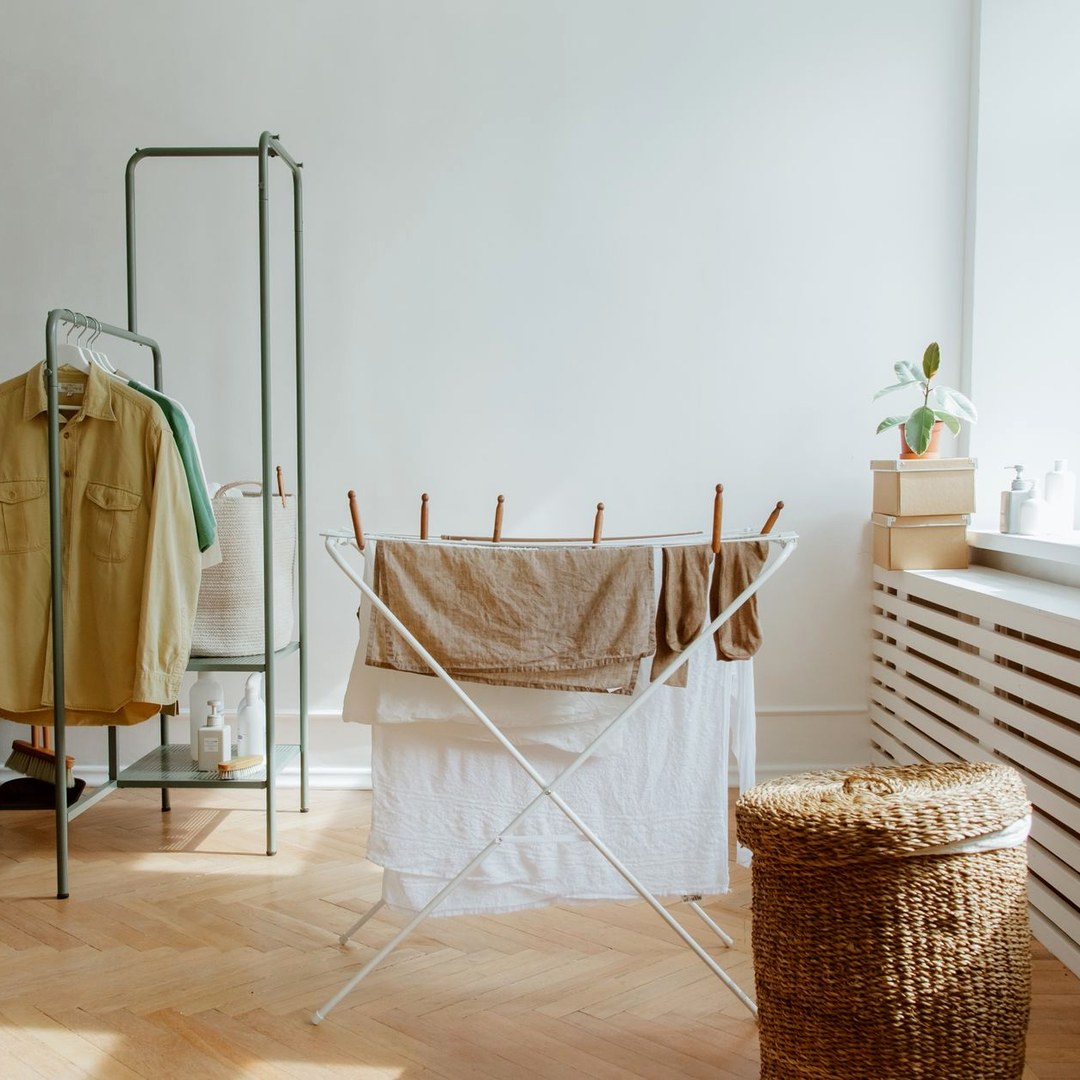 明るい部屋に立てた室内物干しに、白とベージュのリネンが掛けられているようす