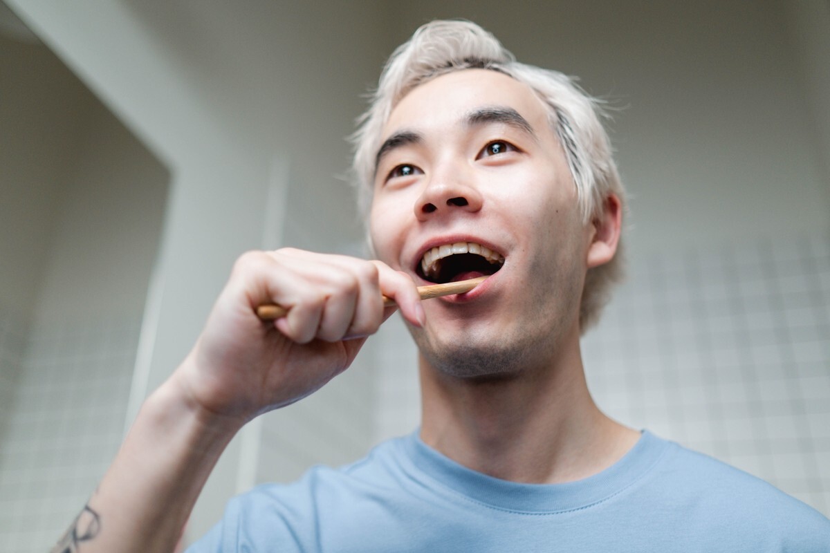 밝은 욕실에서 대나무 칫솔로 평소처럼 양치하는 동아시아계 남성