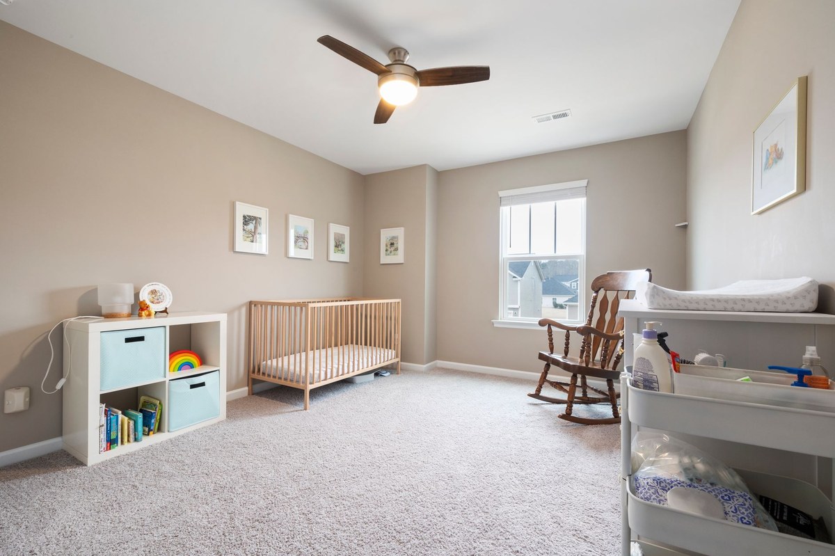 An empty crib with a firm, flat mattress and fitted sheet in a bright, minimalist nursery