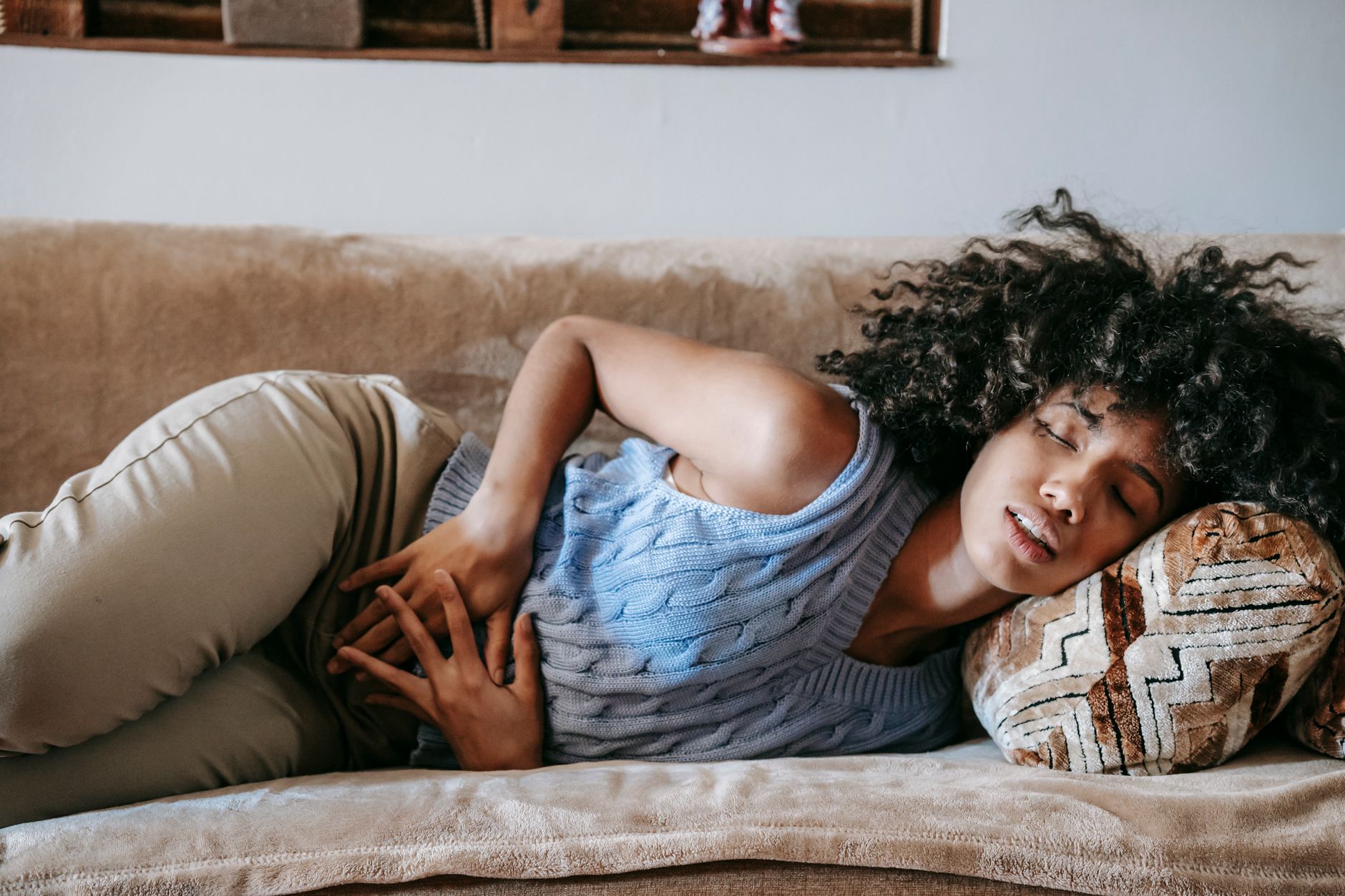 A woman resting a hand low on one side of her abdomen, feeling a mild mid-cycle twinge