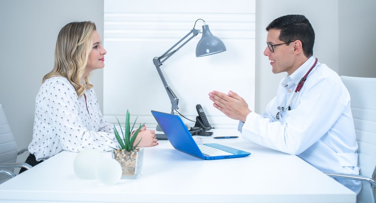 Woman discussing pregnancy confirmation with a healthcare provider in a bright, uncluttered consultation room