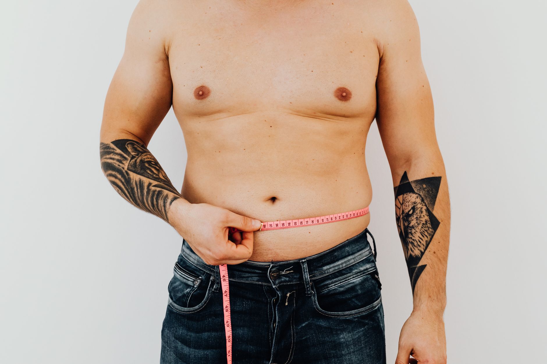 A man measuring his waist with a tape measure