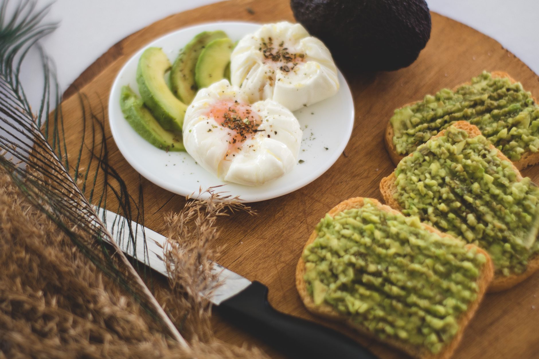 A breakfast plate with avocado, poached eggs, and avocado toast in bright natural light