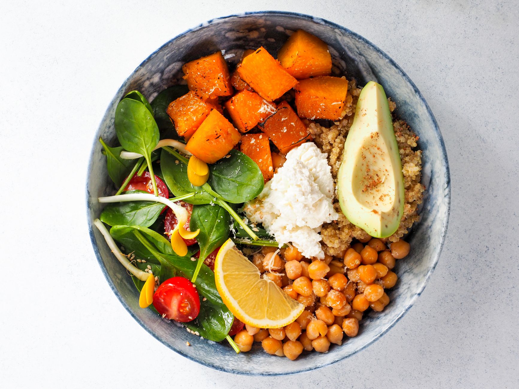 A bright bowl of potassium-rich foods: spinach, avocado, roasted sweet potato and chickpeas