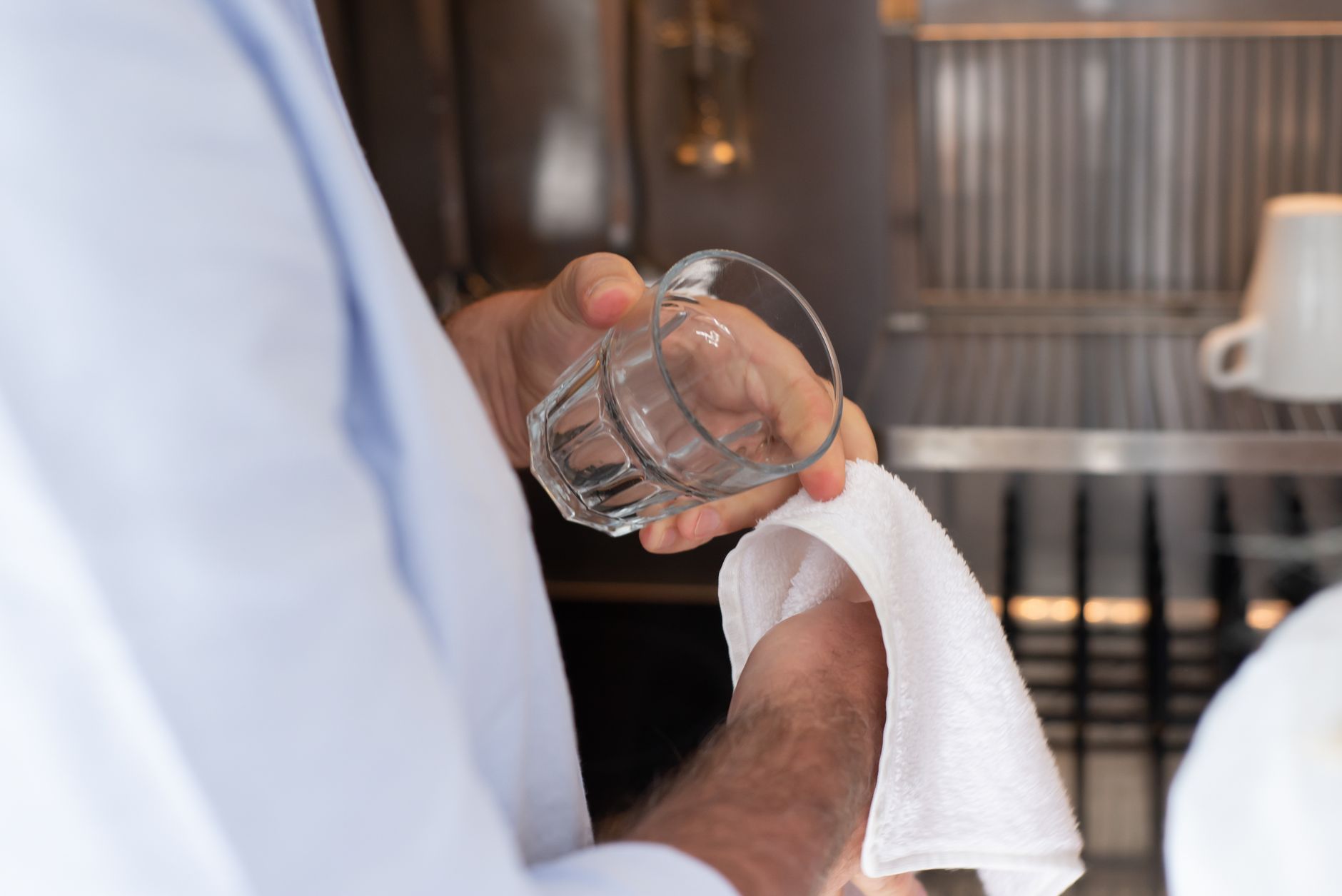 A clean glass being wiped dry with a fresh towel, a reminder that every nebulizer part must be fully dry before it is stored