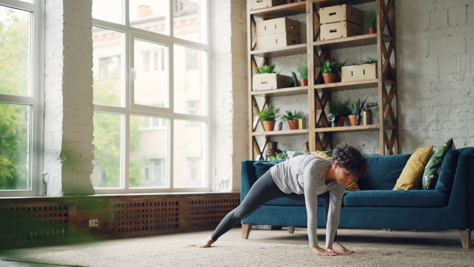 A person doing a light stretch in a bright, plant-filled living room