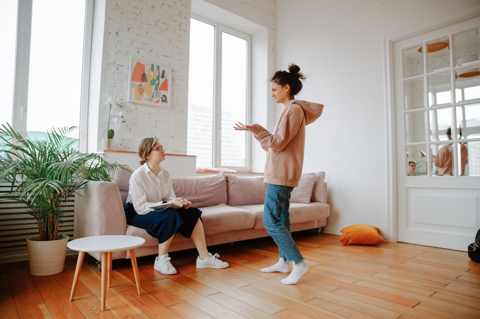 A woman in a bright living room talking with a therapist during a CBT session