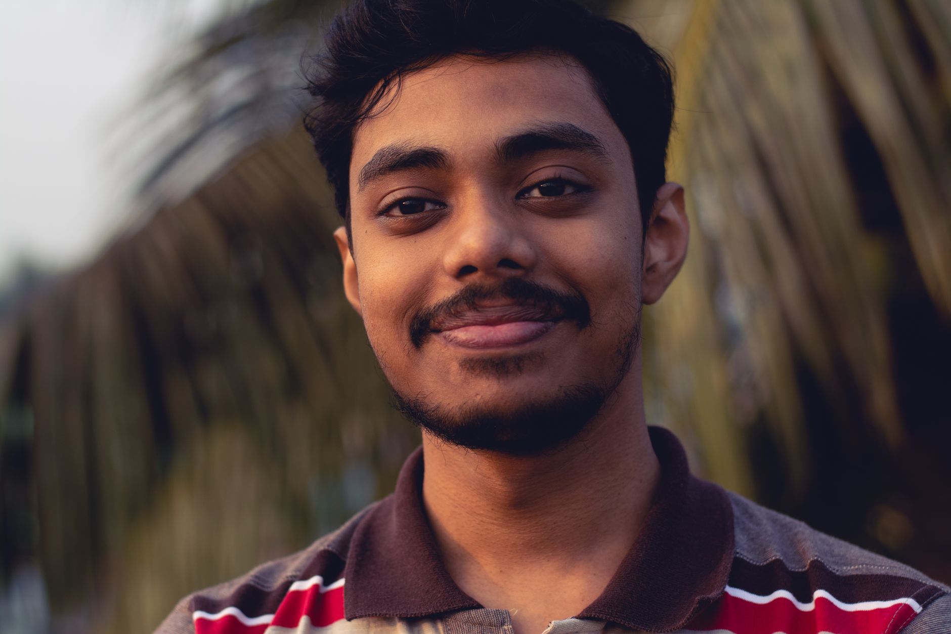 A young man smiling in warm natural light, a reminder that HPV vaccination protects men too