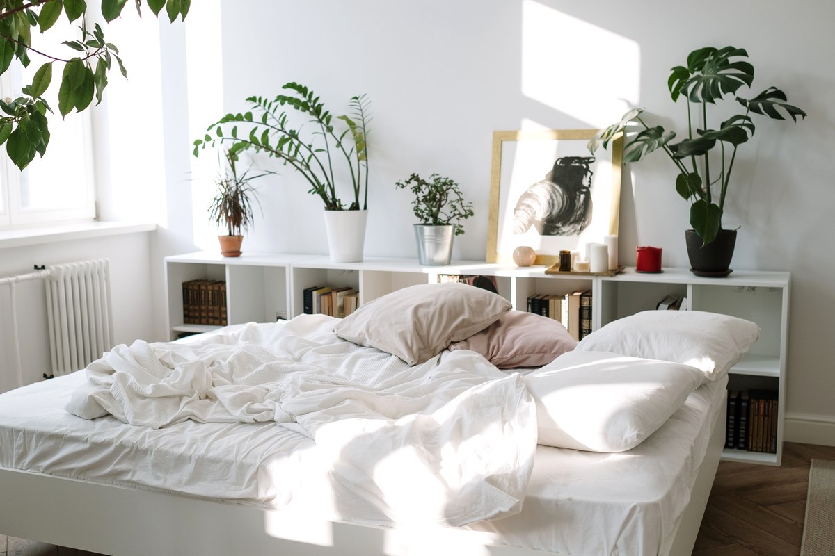 Rumpled white bedding in a bright bedroom with morning sunlight falling across the sheets