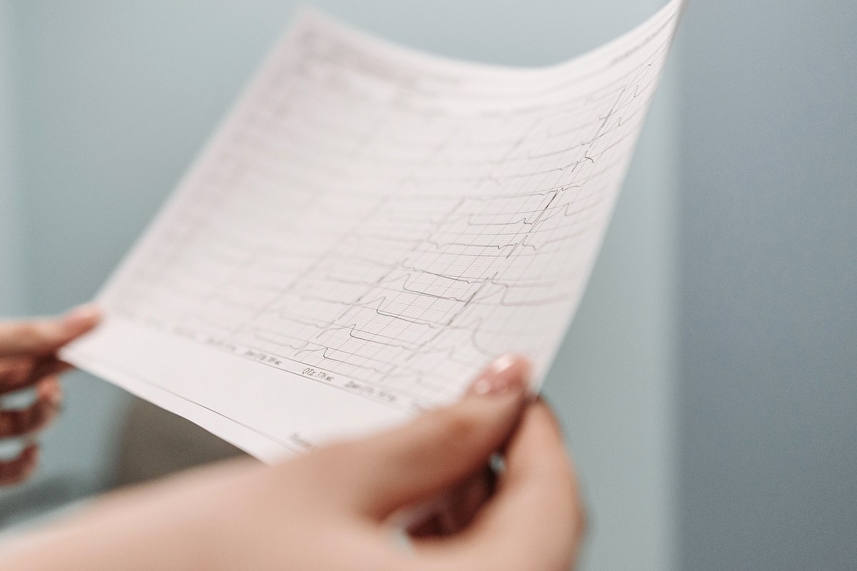 A pair of hands holding a printed test result page, face not visible, soft daylight