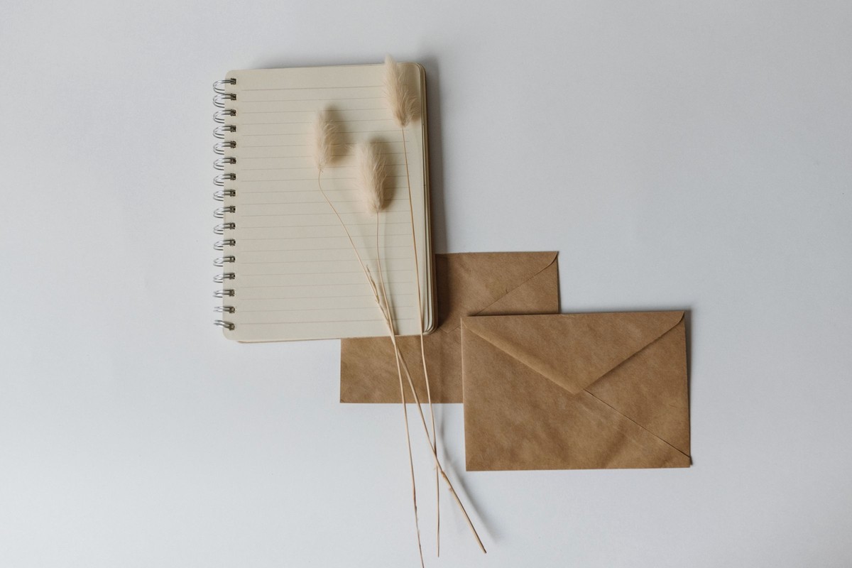 A lined notebook and two kraft mailing envelopes laid out on a pale surface, the everyday materials of a mail-in short-term radon test
