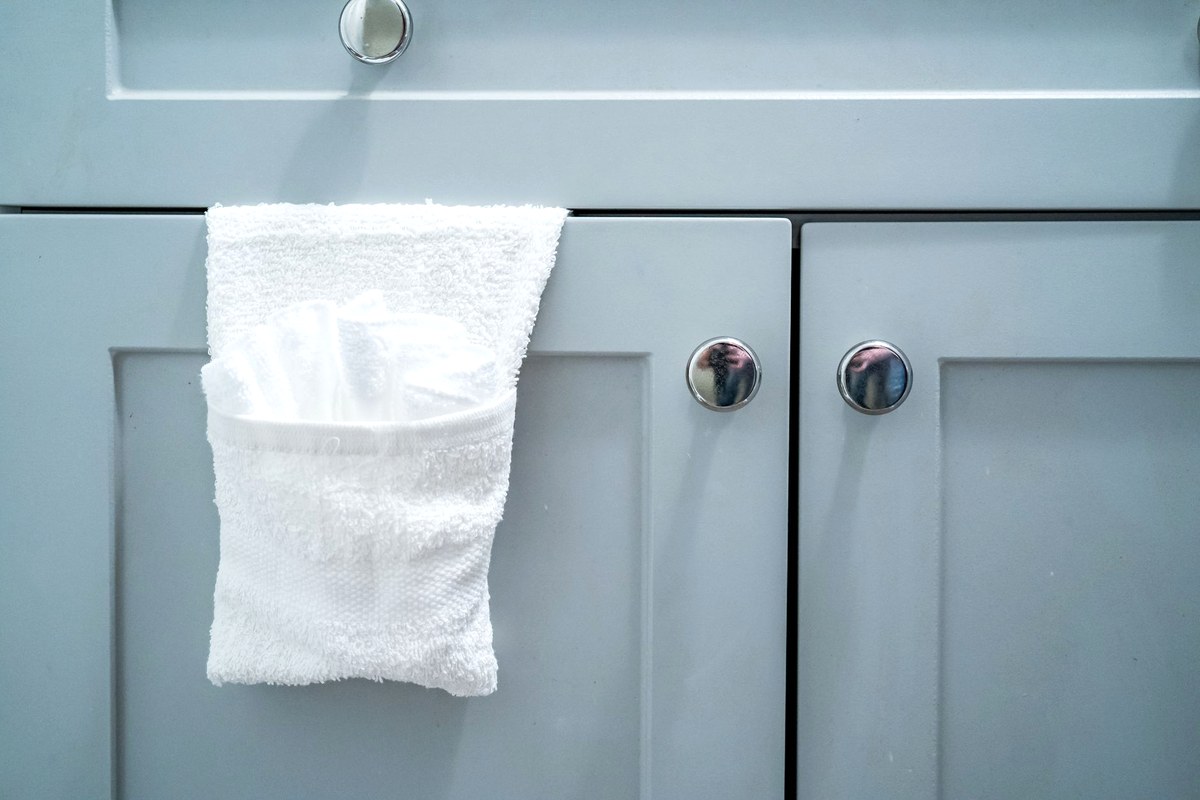A folded white washcloth hanging over the door of a pale blue bathroom vanity