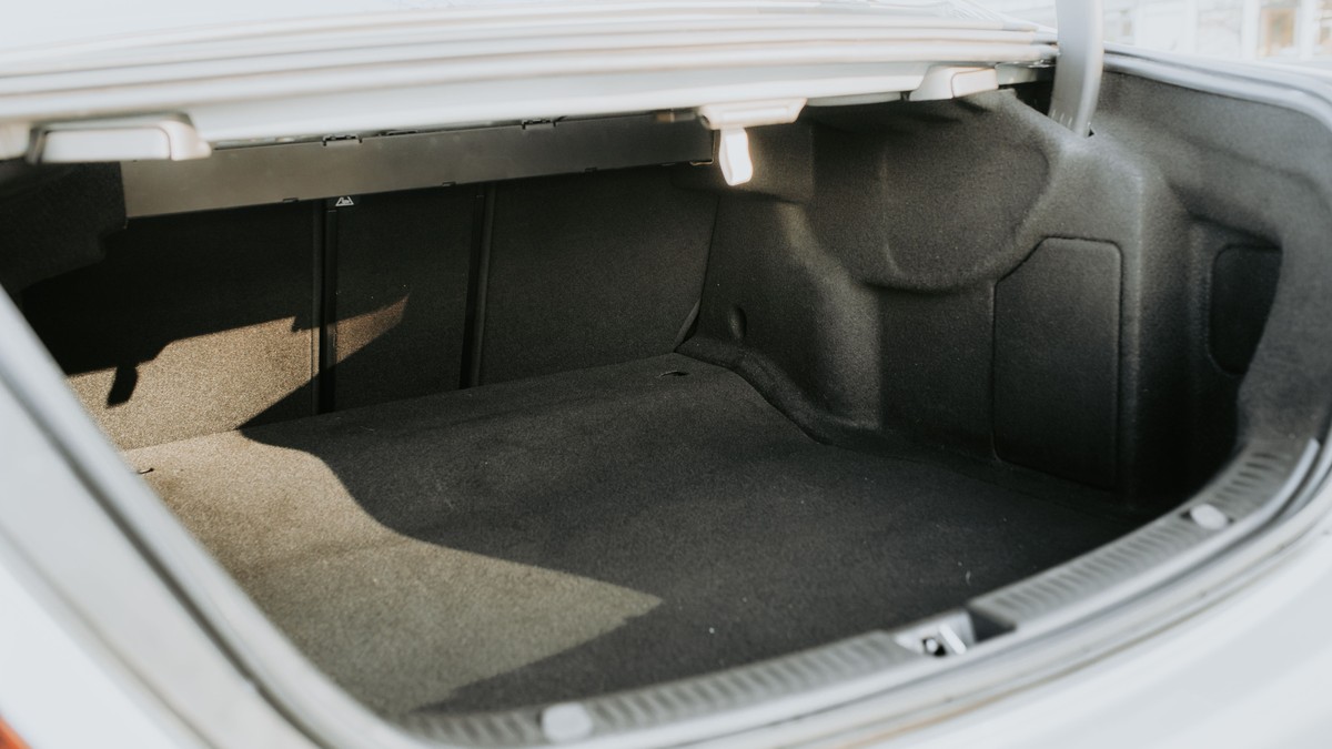 The empty trunk of a sedan with the lid raised, lit by bright daylight