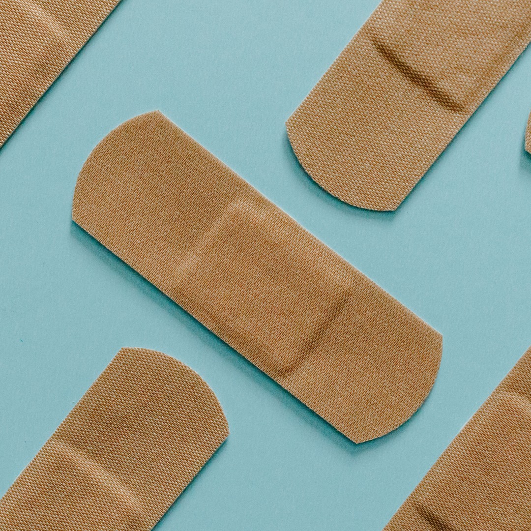 Plain fabric adhesive bandages laid out on a pale blue surface