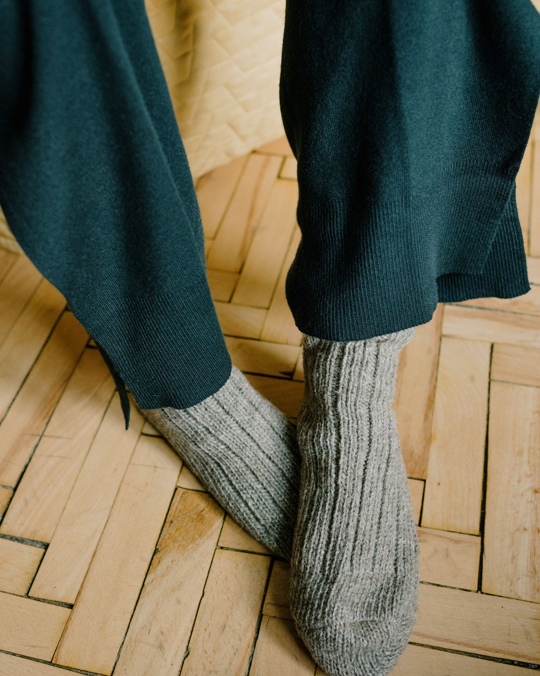 Feet in thick gray wool socks on a wooden parquet floor